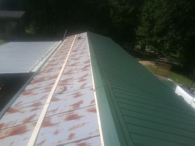 Old rusted panels beside newly installed green metal roofing — Wind Damage Roof Repair by Roofing Brothers in Audubon