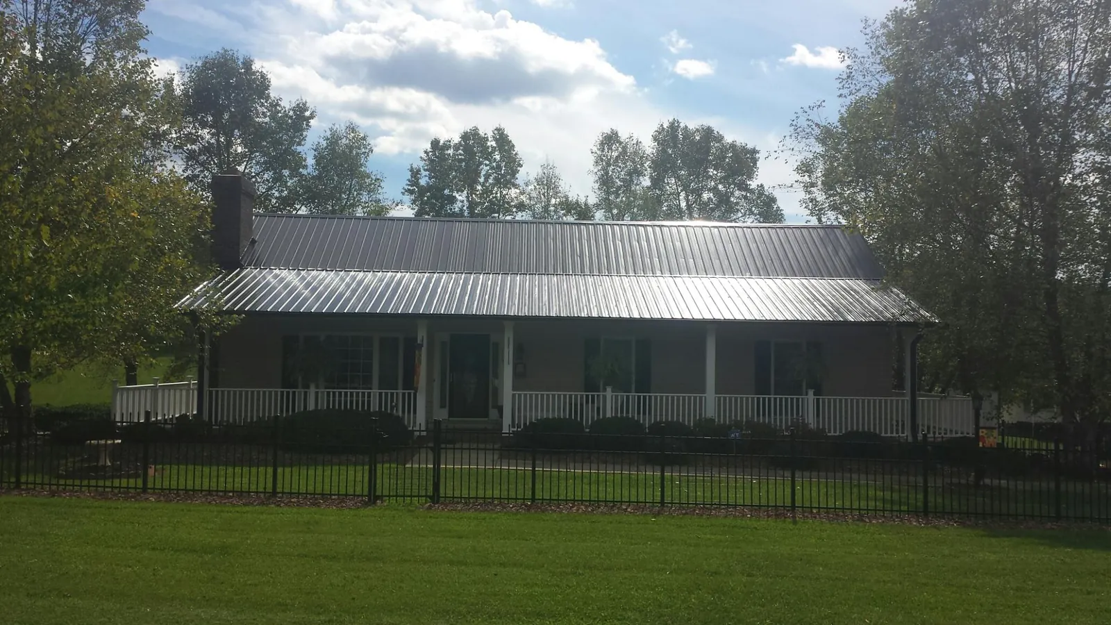 Gray metal roof on a brick ranch with a full width front porch — Gutter Guard Installation work by our crew in Audubon
