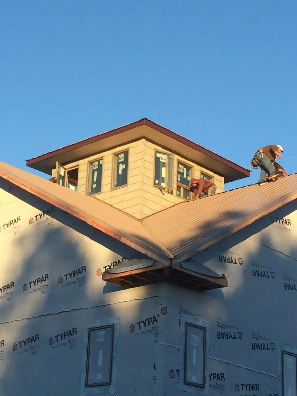 Roofers working around a rooftop cupola on a new metal roof at sunset — Roof Waterproofing in Audubon by Roofing Brothers